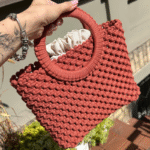 Sodriai oranžinės spalvos macrame rankinė Maia miesto fone