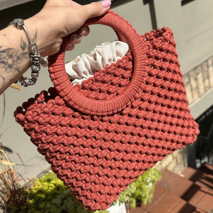 Sodriai oranžinės spalvos macrame rankinė Maia miesto fone